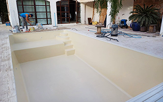 Application de couches de gelcoat pour la rénovation de la piscine coque Photo de la piscine après application du gelcoat beige lors de la rénovation de la coque